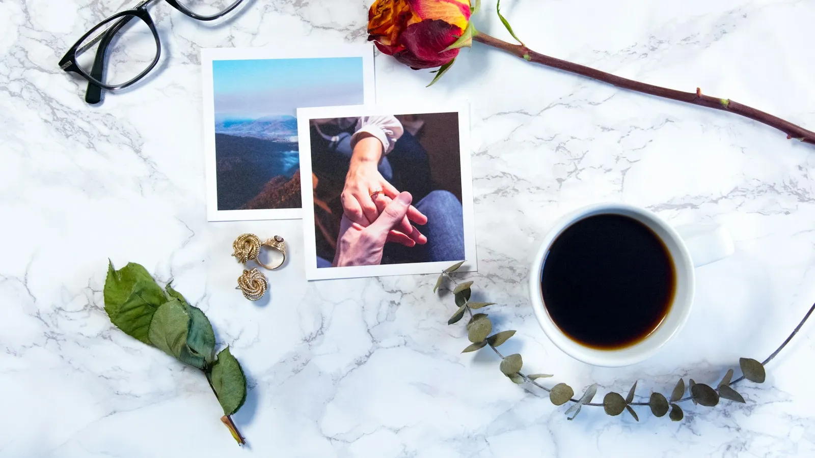 Flat lay on marble with two printed vertical photos, glasses, a rose and a cup of coffee: pin images come in more than one shape and size