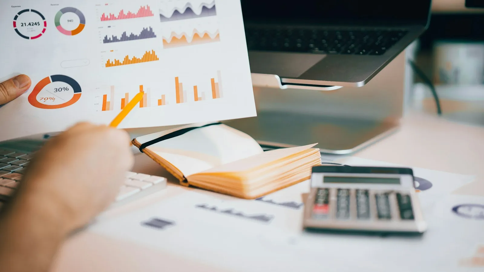 Person at a desk reviewing printed charts next to a laptop and taking notes during a monthly Pinterest analytics review